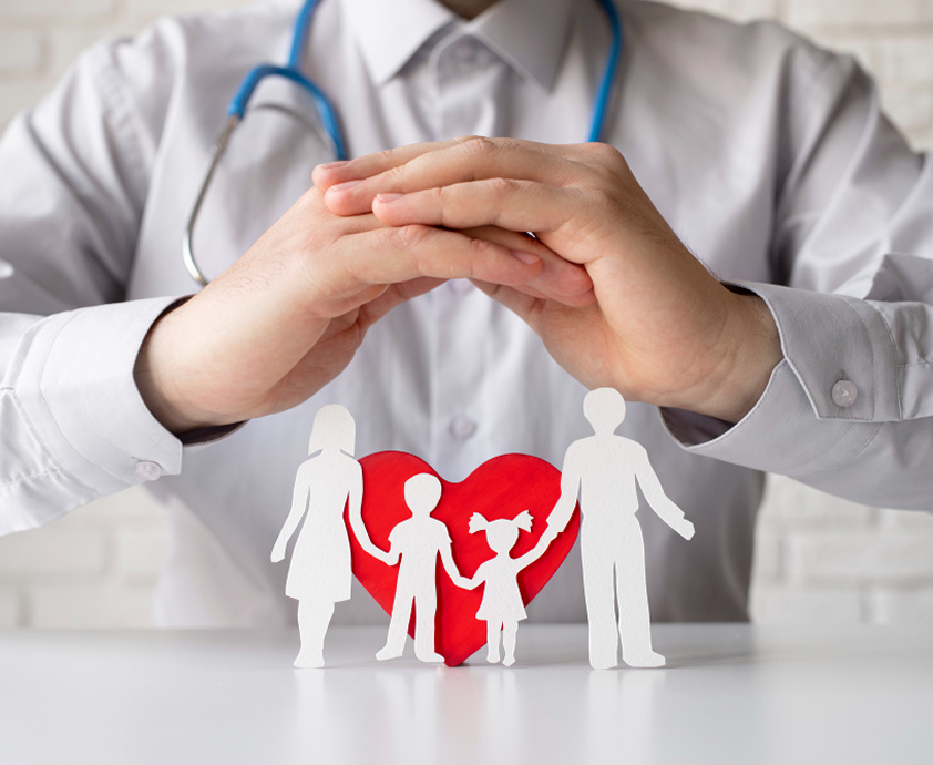 Doctor's hands cupped protectively over a paper cutout of a family