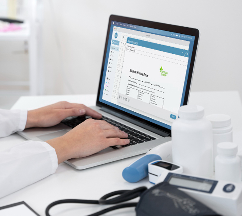 Hands typing on a laptop at a healthcare workstation